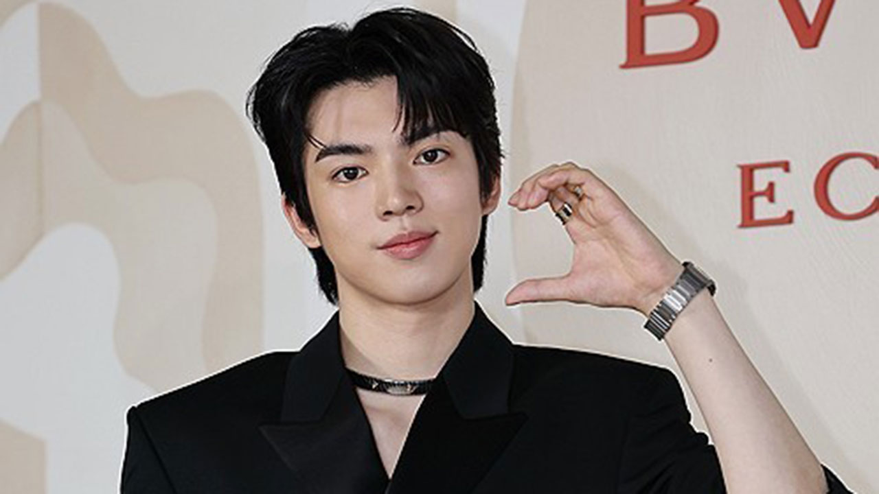 놀이공원 입구 앞에서 직원 유니폼을 입고 일하는 아르바이트생