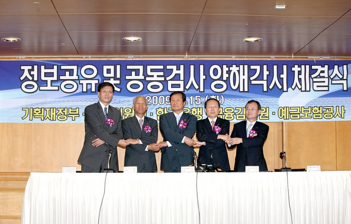 보험 약관 책자를 펼쳐 놓고 암 분류표 페이지를 손가락으로 짚으며 읽는 모습