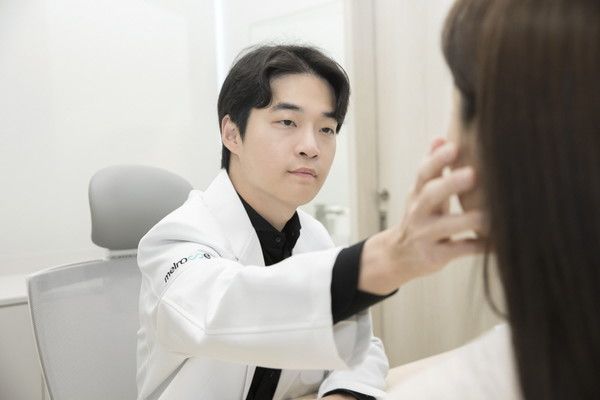 시술 후 붉어진 얼굴 피부를 거울로 살펴보는 모습