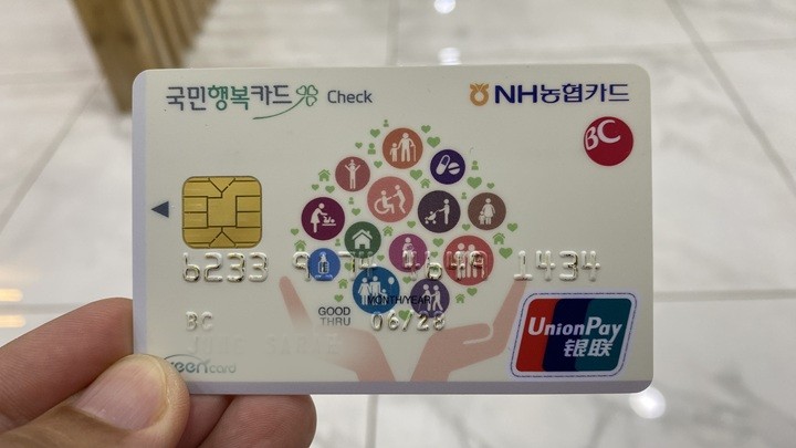 병원 접수 창구에서 카드 결제 단말기에 카드를 대는 손, 결제 영수증이 일부 보이는 장면